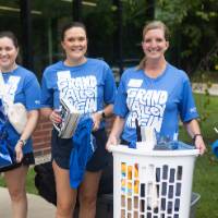 Group of 5 volunteers smiling at camera while they hold items